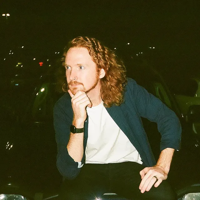 A candid film portrait of Ben sitting on a car at night.