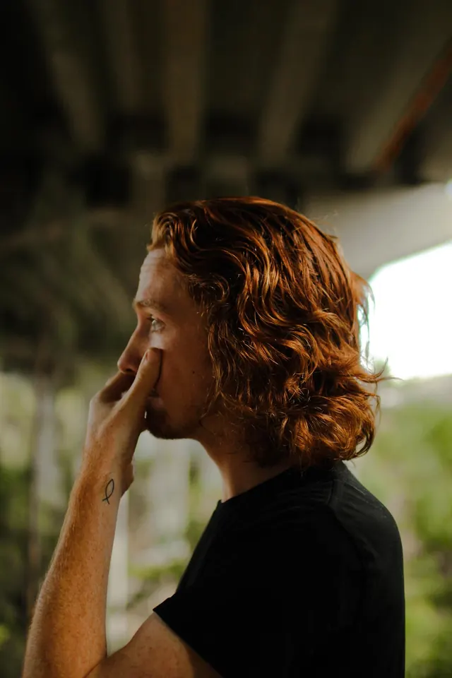 A side profile of Ben with his hand resting on his cheek.