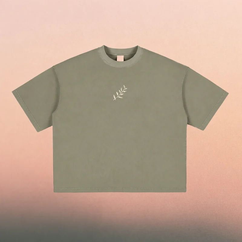 Front mockup — cream olive branch on a washed Gray Green boxy tee